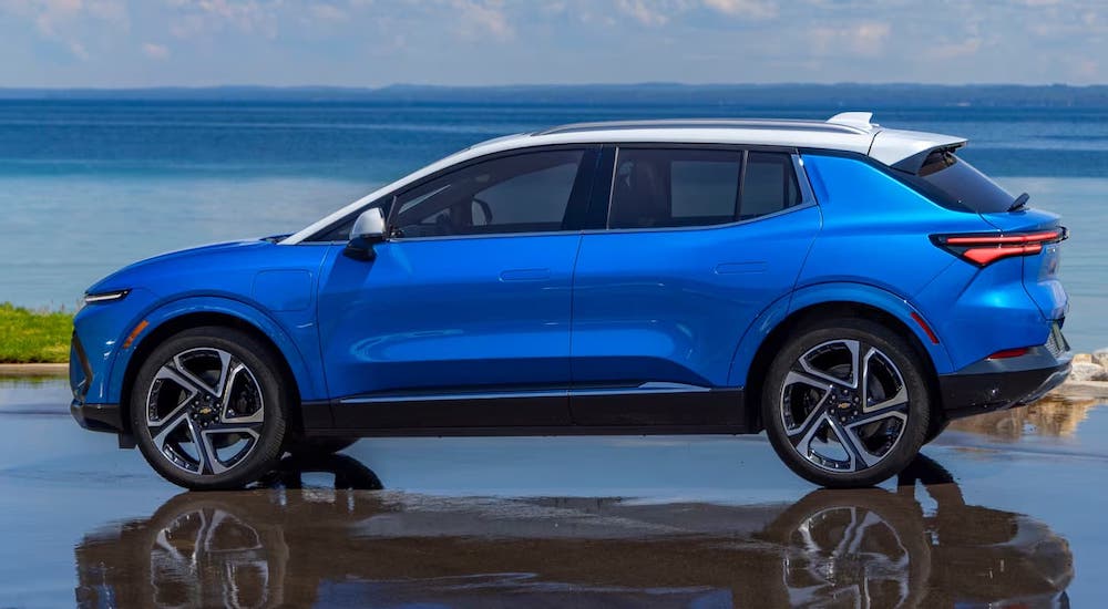 Side view of a blue 2025 Chevy Equinox EV parked on a wet pavement.