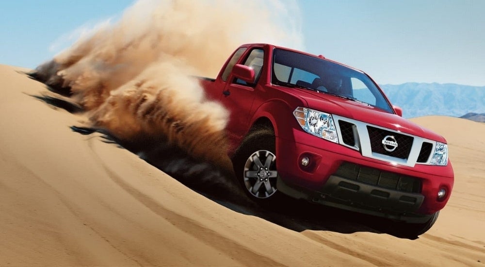 A red 2017 Nissan Frontier kicking up dust off-road.