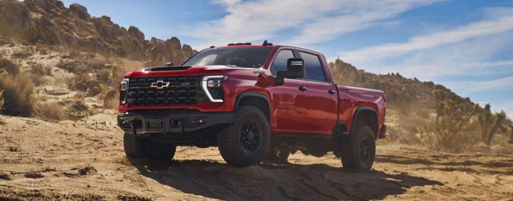 Red Chevy Silverado parked on a dirt road.