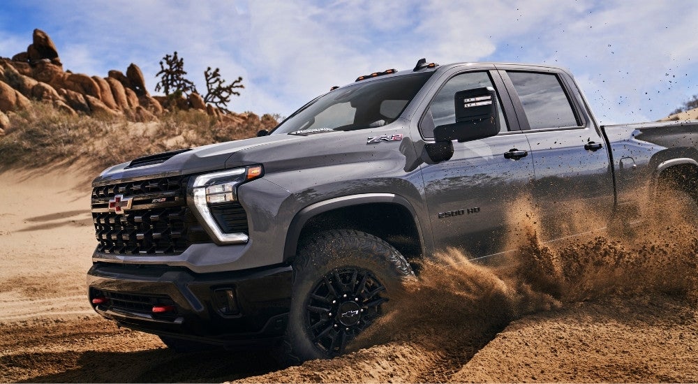 A grey 2024 Chevy Silverado 2500 HD ZR2 kicking up dust off-road.