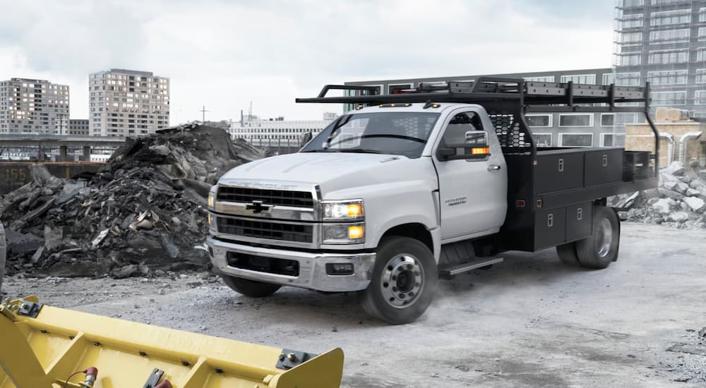 White 2025 Chevy Silverado 5500HD driving through a construction site.