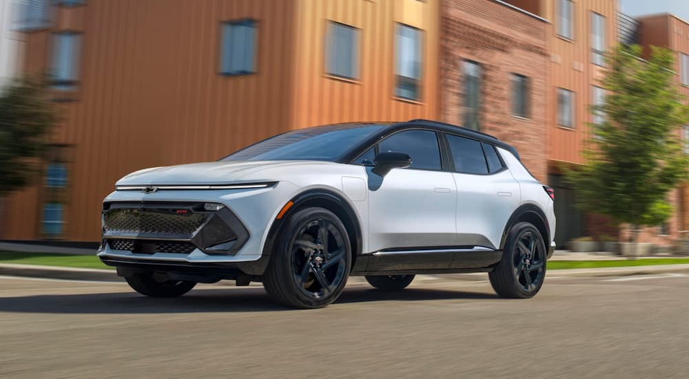 A white 2025 Chevy Equinox EV driving through a city.
