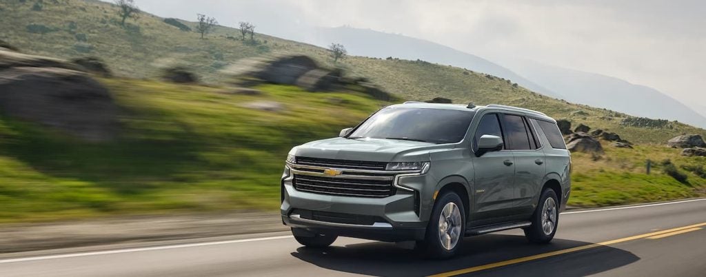 A silver Chevy Tahoe driving in the countryside.