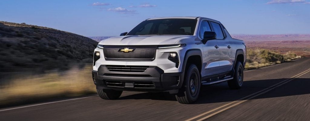 White Chevy Silverado EV RST driving on a road.