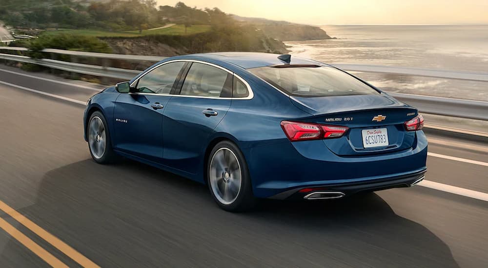 Blue 2022 Chevy Malibu driving past an ocean.