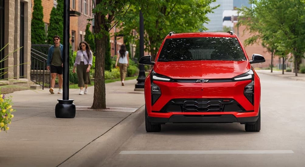 A red 2027 Chevy Bolt RS parked in a city.