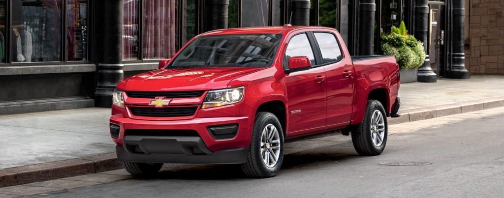 A red Chevy Silverado parked by a building.