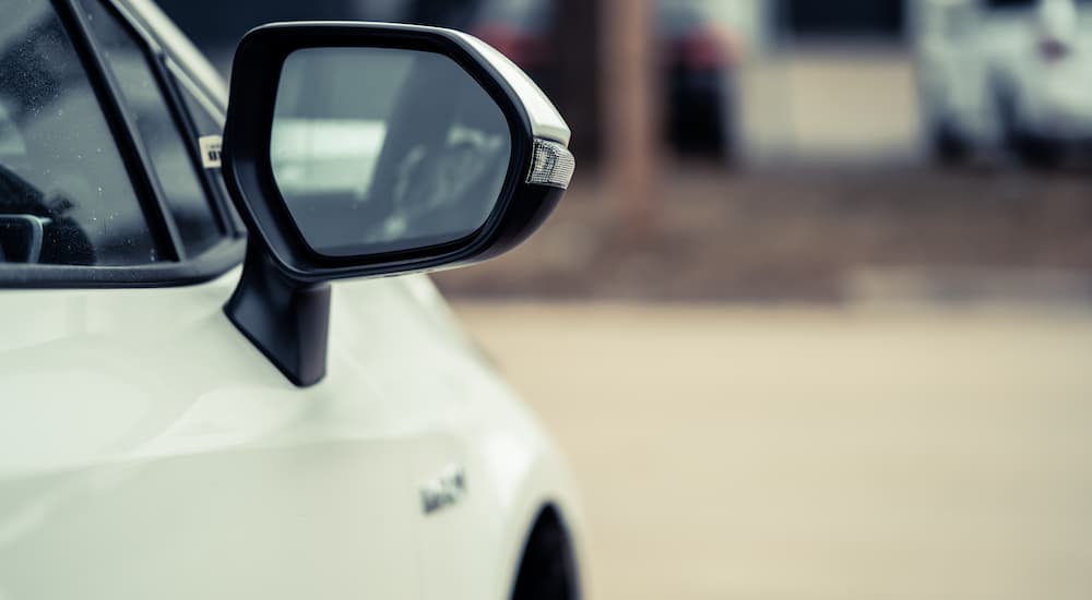 Side mirror on a white vehicle that's for sale.