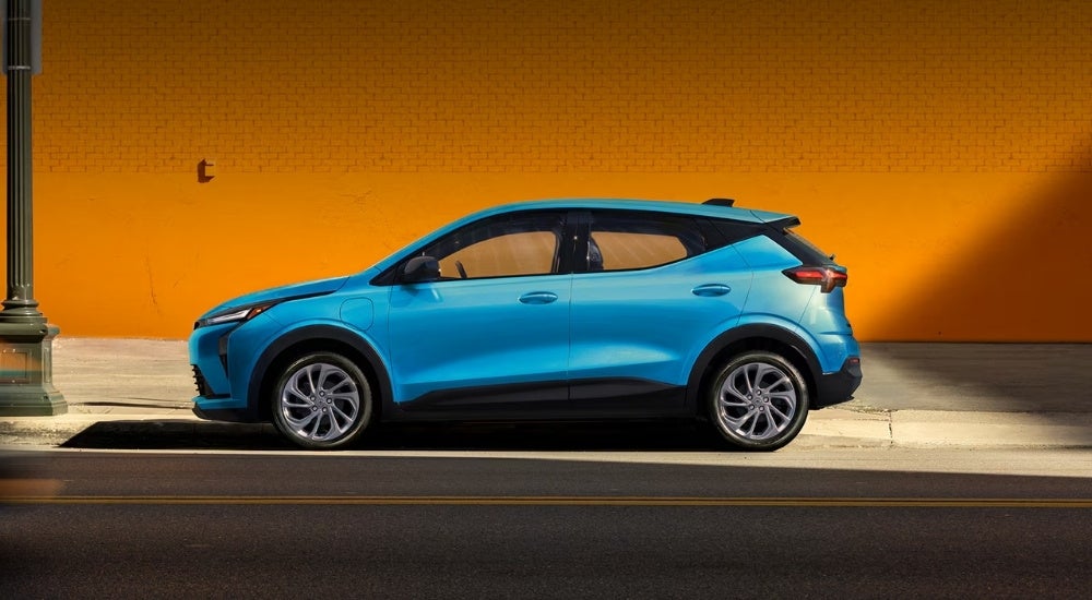 A blue 2027 Chevy Bolt parked on a city street