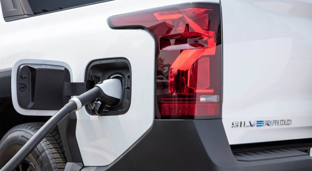 Close-up on the taillight and charging port of a white 2025 Chevy Silverado EV WT.