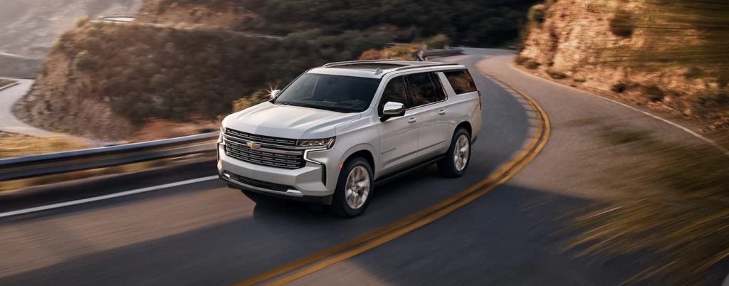 White Chevy Tahoe driving on a winding back road.