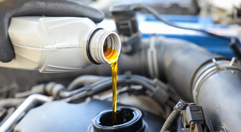 A white oil can being poured into an engine.