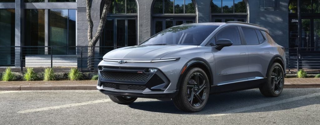 A grey 2025 Chevy Equinox EV parked in front of a building.