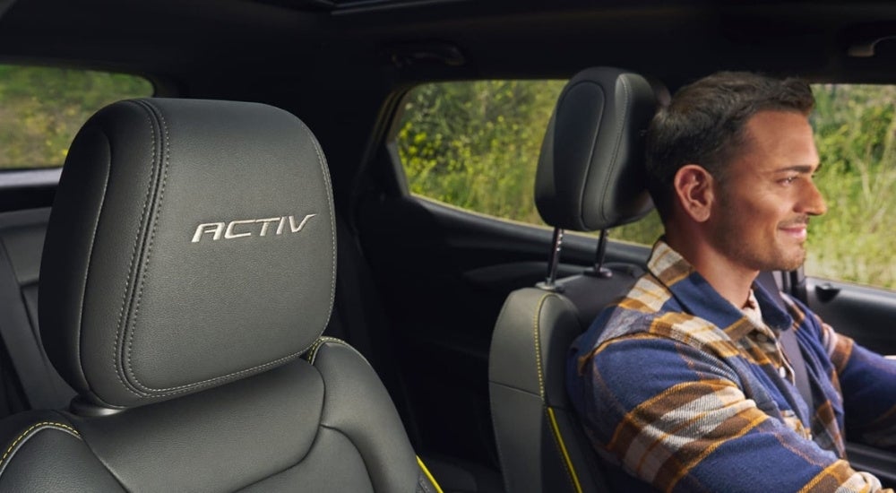 A smiling person driving a 2024 Chevy Trailblazer ACTIV.