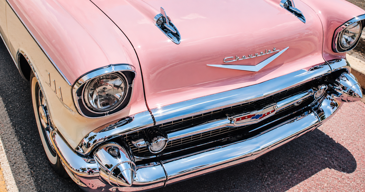 a soft, pastel pink two toned Chevy on the street.