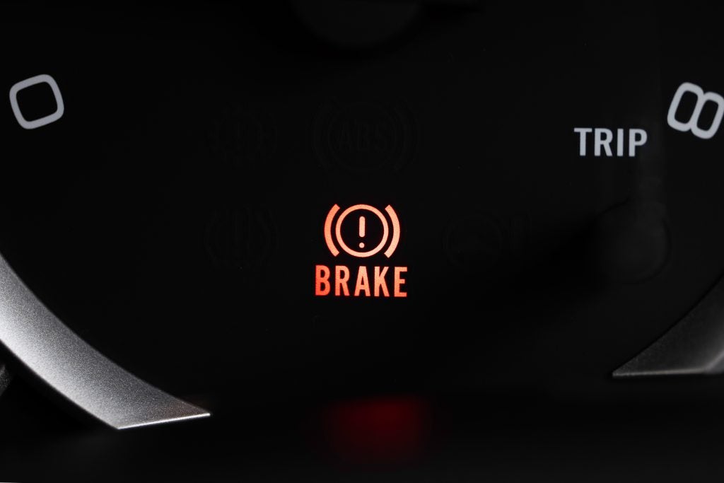 Red brake warning light illuminated on a car dashboard display.