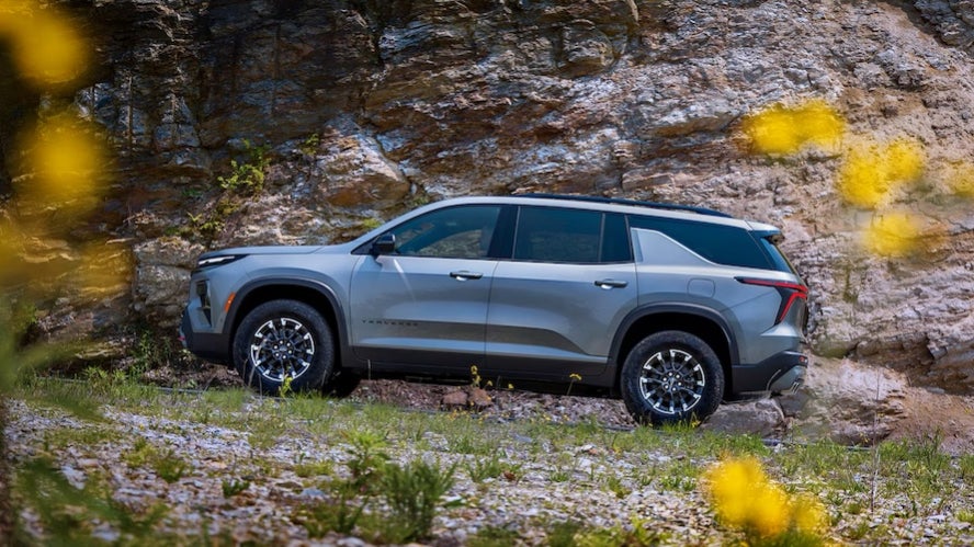 A silver 2027 Chevy Traverse parked beside a rockface