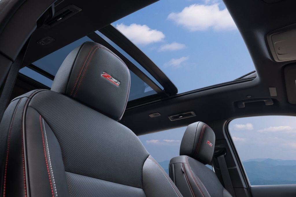 View of Z71 badge on passenger’s seat in 2024 Chevrolet Traverse Z71 with Jet Black with Red accents interior. 