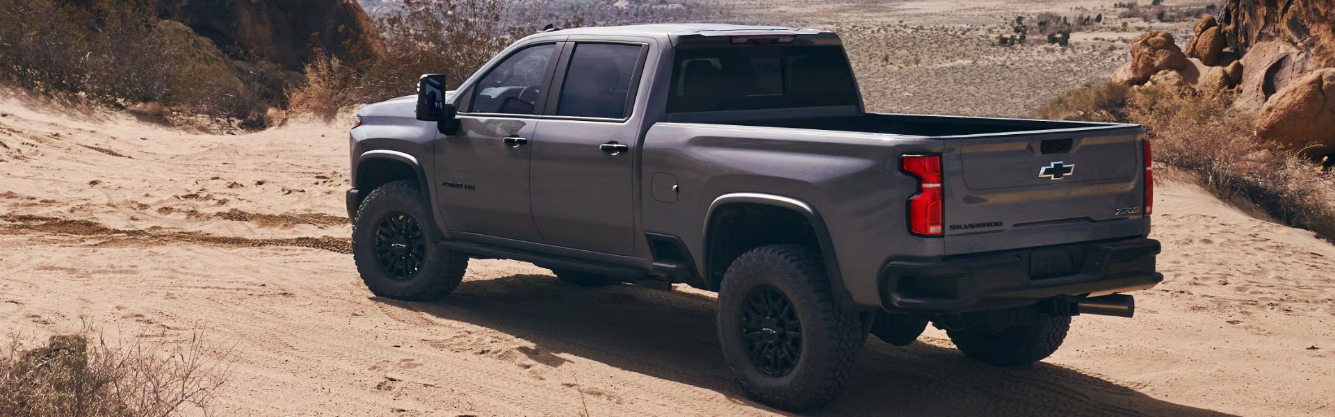 2025 Chevrolet Silverado 1500 driving off-road on a sandy desert trail, showcasing its rugged performance and capability.