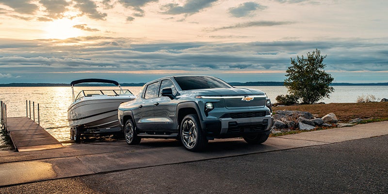 Chevrolet Silverado parked at sunset, showcasing its sleek design against a vibrant orange and purple sky.