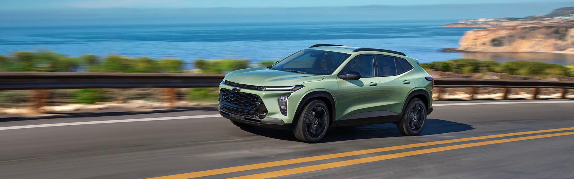 2025 Chevrolet Trax driving on a coastal highway with ocean views and cliffs in the background
