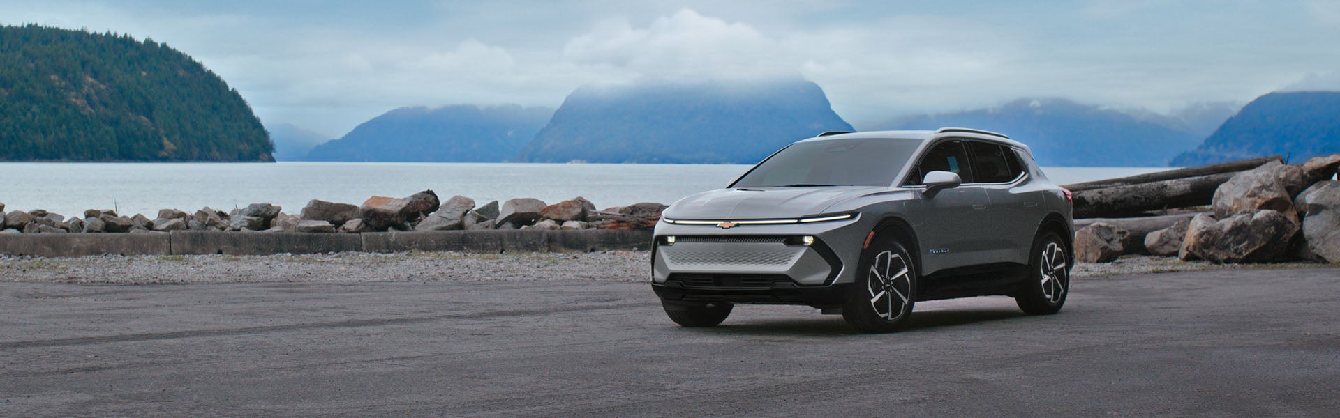 2026 Chevy Equinox EV parked beside a scenic waterfront with mountains in the background