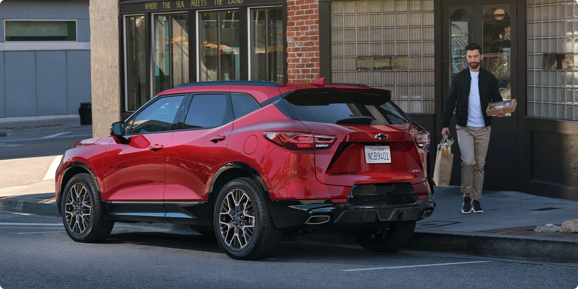 A shopper walking past a Chevrolet Blazer parked on a downtown street