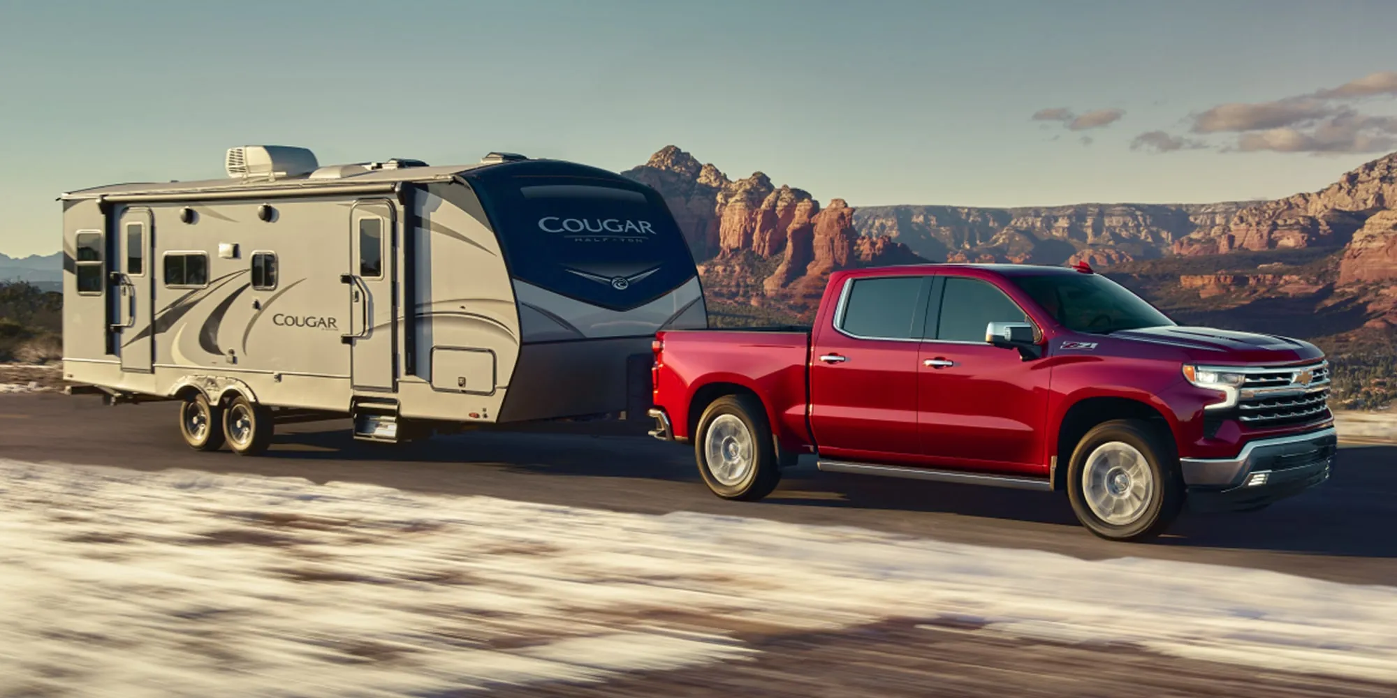 A red Chevrolet Silverado towing a camper trailer