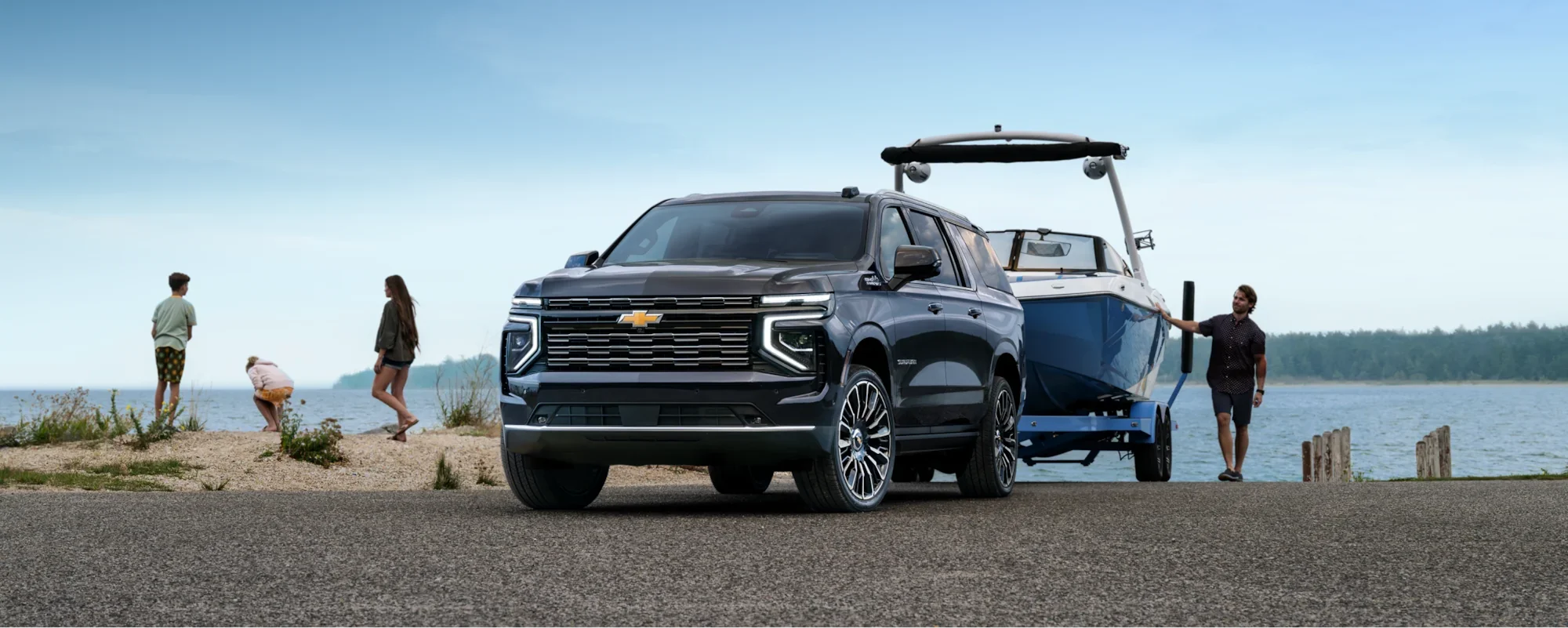 A man beside a boat trailer hitched to a Chevrolet Suburban at the lakeshore
