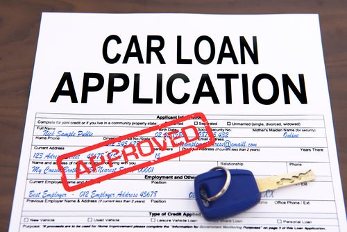 Approved car loan application form and key on desktop
