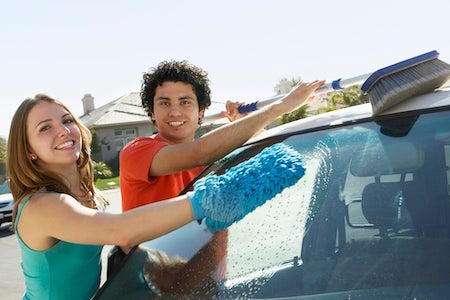 Portrait of a happy multiethnic couple washing car together