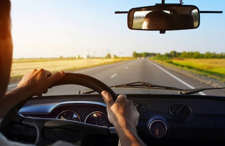 Driver's hands on steering wheel of a car