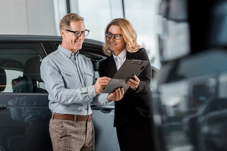 People looking at clipboard at dealership