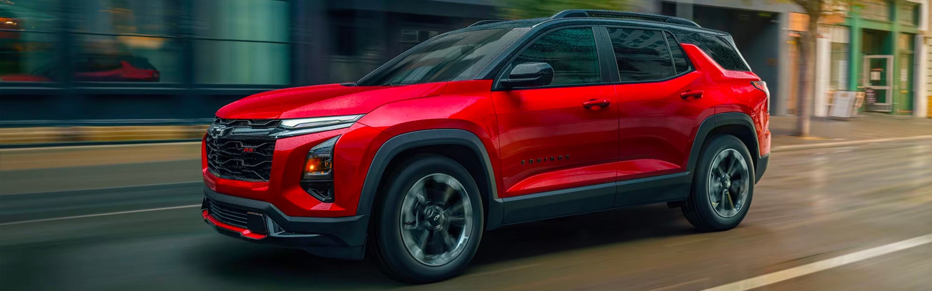Red 2026 Chevrolet Equinox driving on a city street during rain.