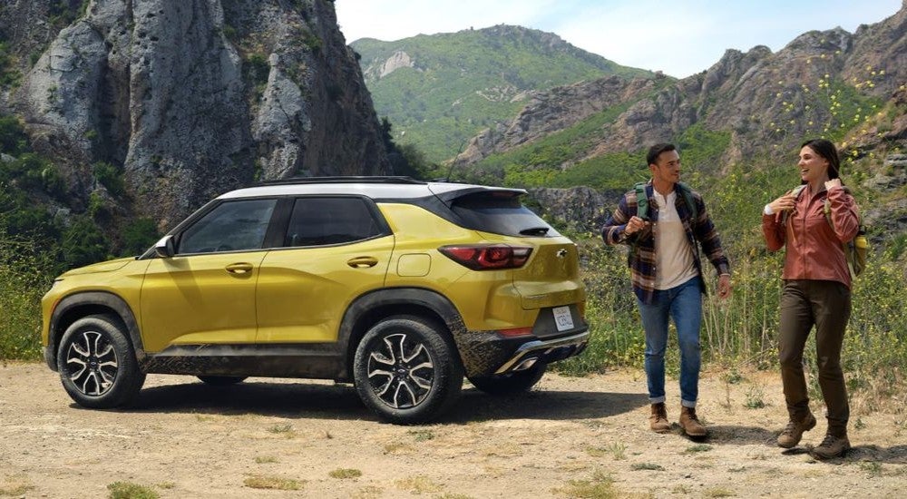 A yellow 2024 Chevy Trailblazer foe sale parked next to a hiking trail.