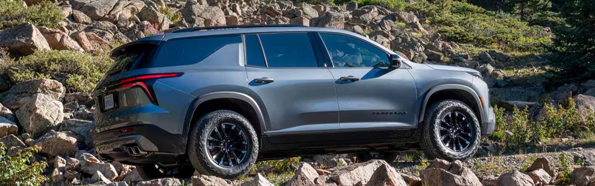 2025 Chevrolet Traverse SUV driving on a rocky mountain trail, highlighting its off-road performance, rugged design, and advanced all-wheel-drive capability.