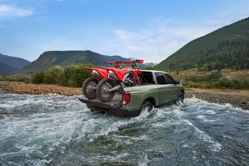 2026 Honda Ridgeline Trailsport driving through water with cargo in the truck bed