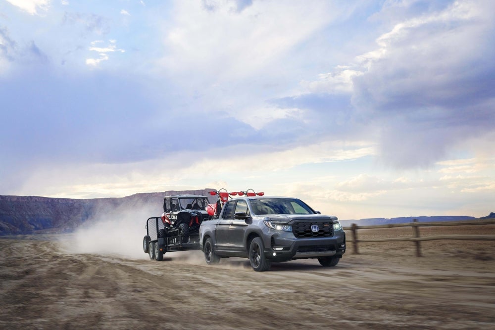2026 Honda Ridgeline Trailsport driving through dusty road with cargo in the truck bed