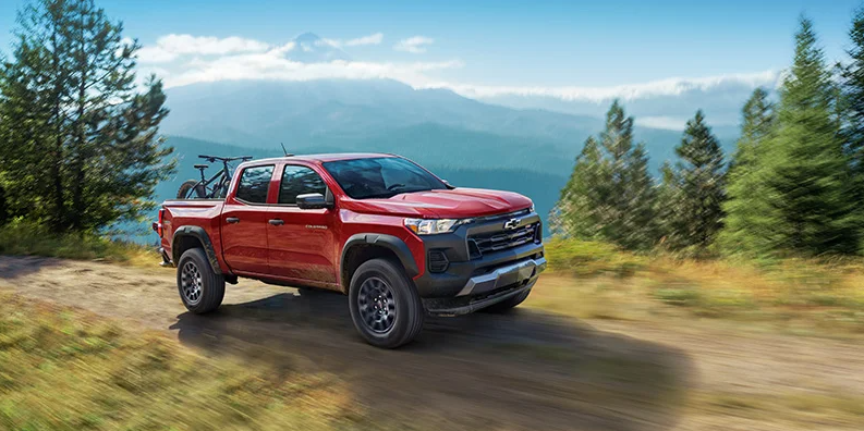 A red 2026 Chevy Colorado driving down a dirt road.