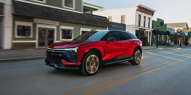 Red Chevrolet Blazer EV driving down a town street.