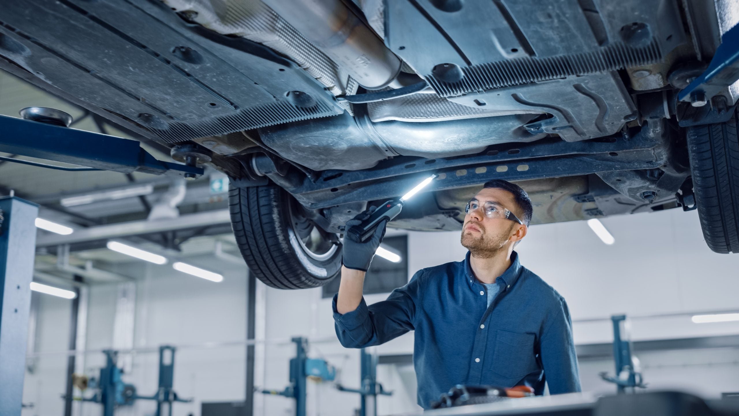 Mechanic inspecting the underside of a car using in an auto repair shop
