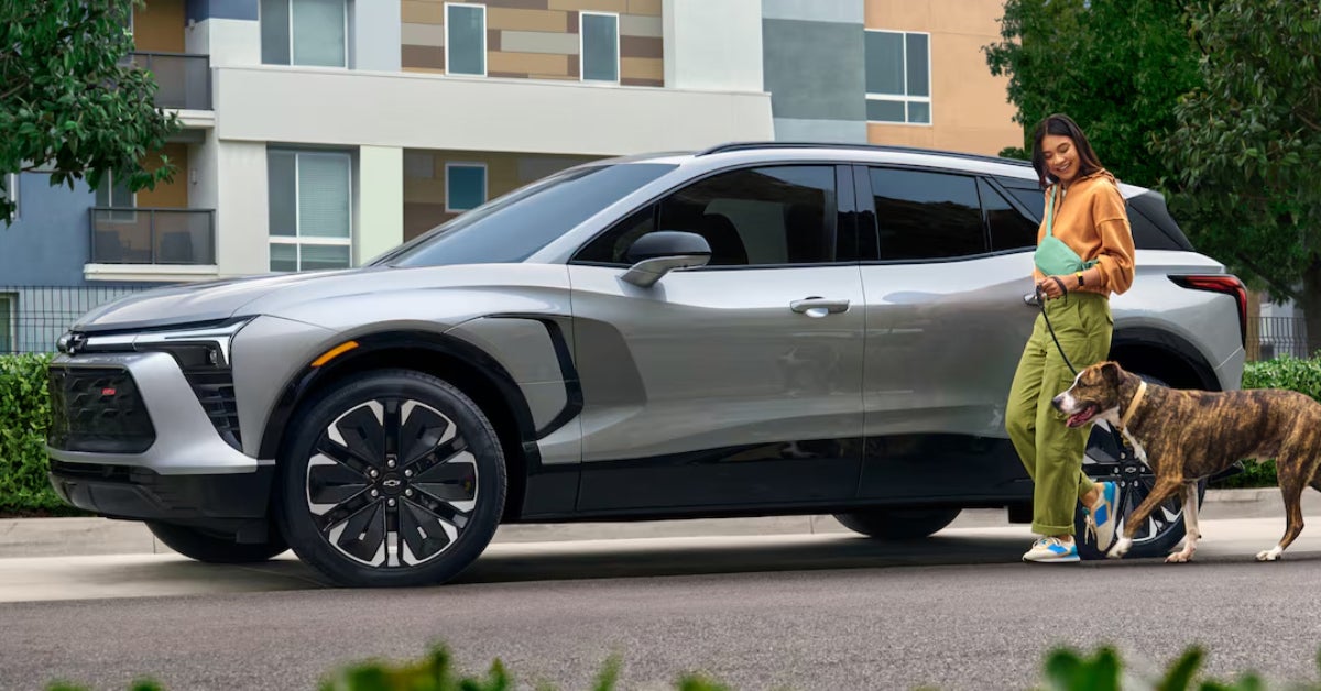 image of a parked 2025 Blazer EV and a woman walking her dog
