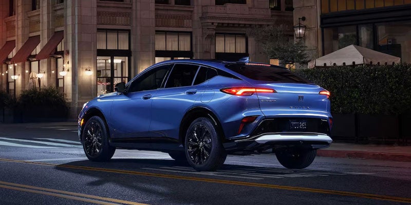 A sleek blue Envista is parked on a quiet, dimly lit city street at night. The vehicle's modern design and illuminated taillights suggest elegance and sophistication.