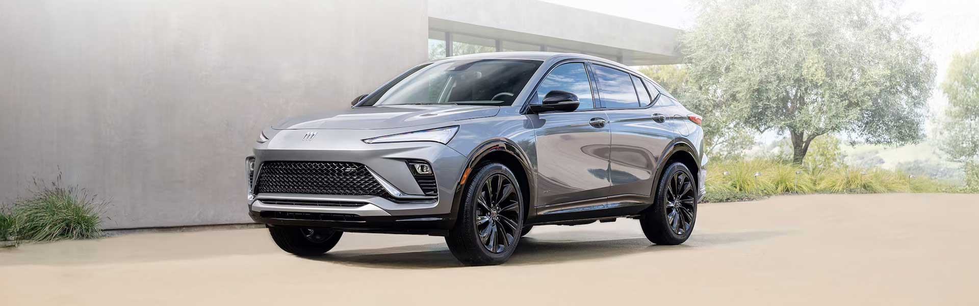 2025 Silver Buick Envista parked in a modern residential driveway with landscaped greenery in the background.