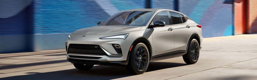 2026 Buick Envista crossover SUV in motion on a city street, showcasing sleek coupe-inspired styling and sporty design.