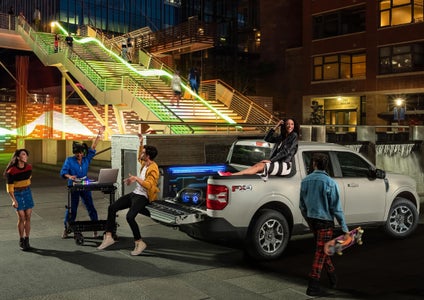 Young people gathered around the open bed of a 2026 Ford Maverick XLT with a DJ set up.