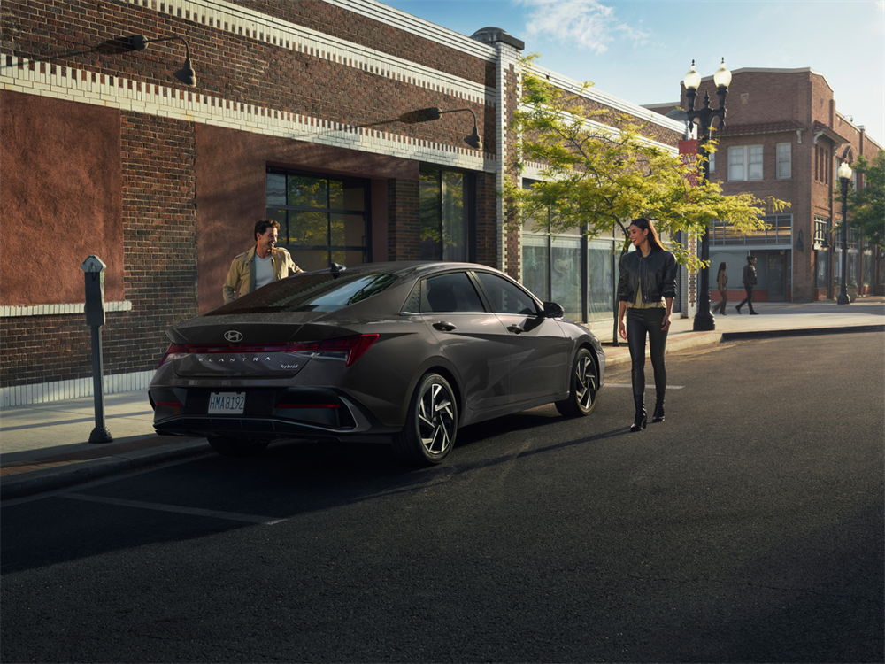 2026 Hyundai Elantra Hybrid parked with a driver and passenger approaching the car