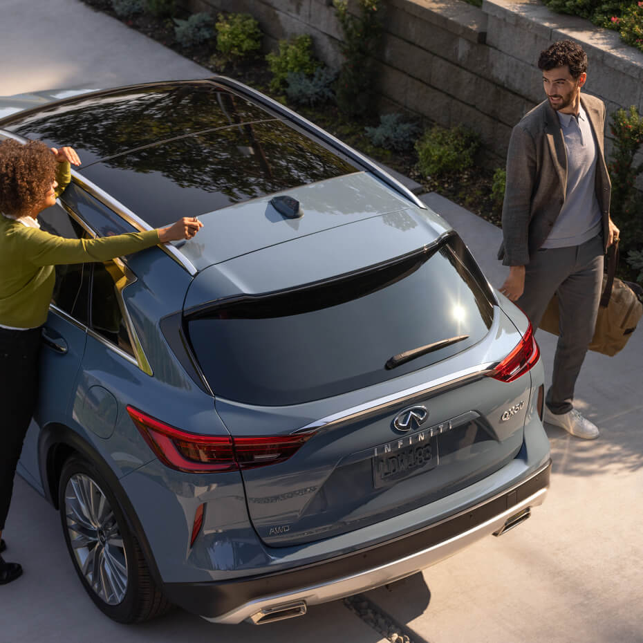 Two people interacting with rear of INFINITI SUV