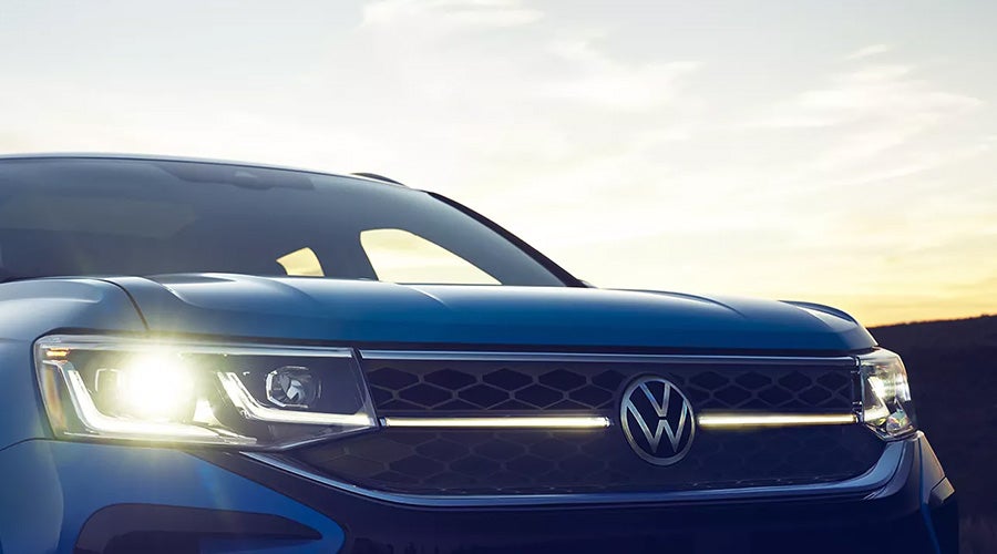 Close-up of the front grille and headlights of a blue Volkswagen SUV at sunset