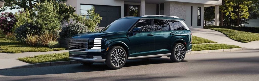 A dark green SUV parked outside a house.